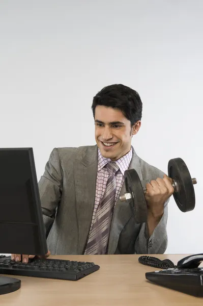 Geschäftsmann trainiert mit Hanteln und arbeitet am Computer — Stockfoto