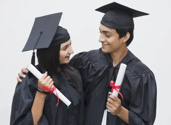 Casal em vestido de graduação titulares de diplomas — Fotografia de Stock