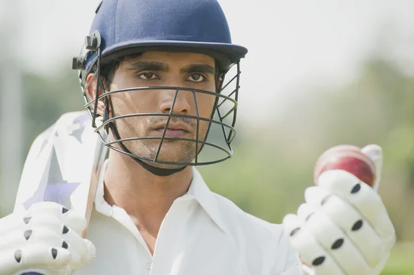 Cricket batsman holding a cricket bat with a cricket ball — Stock Photo, Image