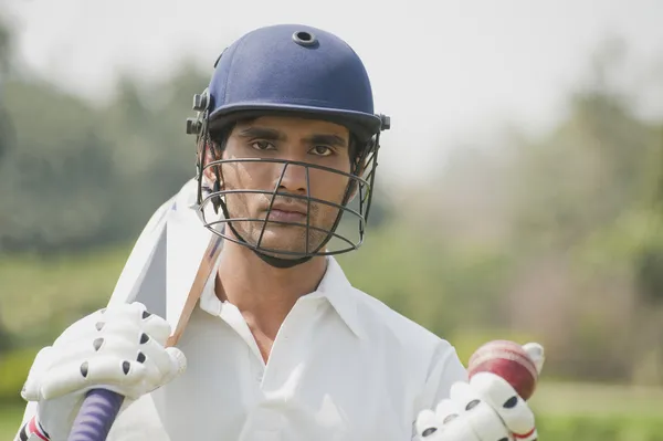 Bateador de cricket sosteniendo un bate de cricket con una pelota de cricket — Foto de Stock