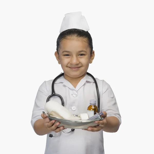 Menina vestida de enfermeira e segurando uma bandeja de medicamentos — Fotografia de Stock