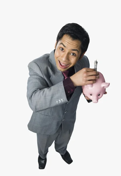 Businessman putting money into a piggy bank — Stock Photo, Image