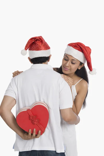 Man hiding a Christmas present to surprise his girlfriend Royalty Free Stock Photos