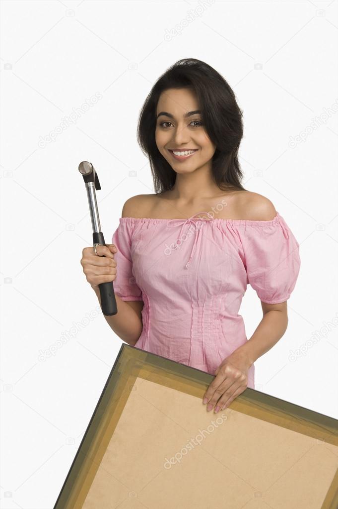 Woman holding a hammer and a picture