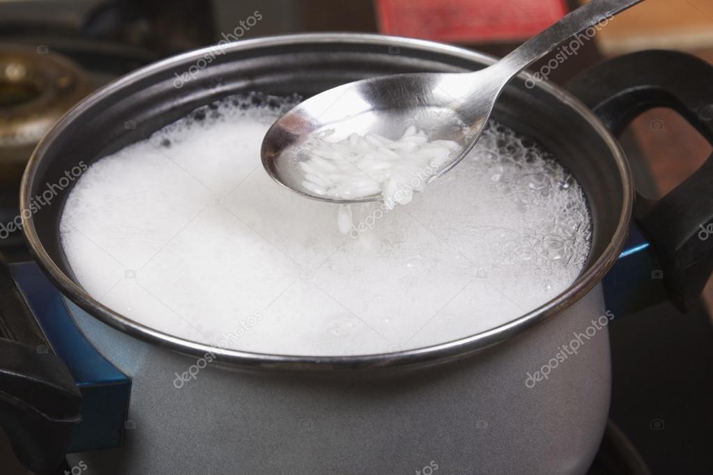 Spoon over a pan of rice boiling on a stove — Stock Photo © imagedb
