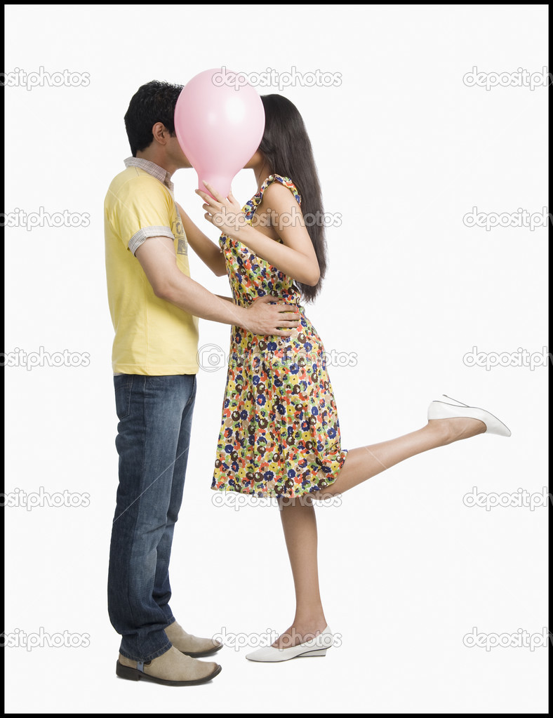 Couple kissing behind a balloon