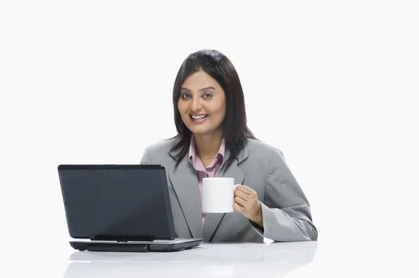 Geschäftsfrau trinkt Kaffee, während sie am Laptop arbeitet — Stockfoto