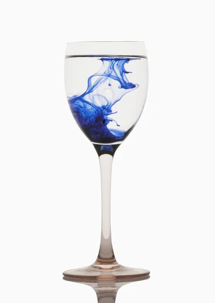Blauwe kleur strepen met water in een glas wijn — Stockfoto