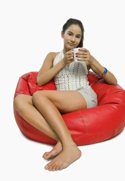 Mujer sentada en una bolsa de frijoles con una taza de café —  Fotos de Stock