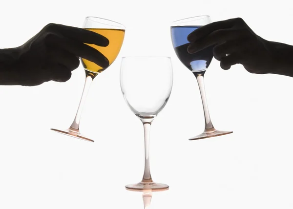 Две руки наливают разноцветные коктейли в бокал вина — стоковое фото