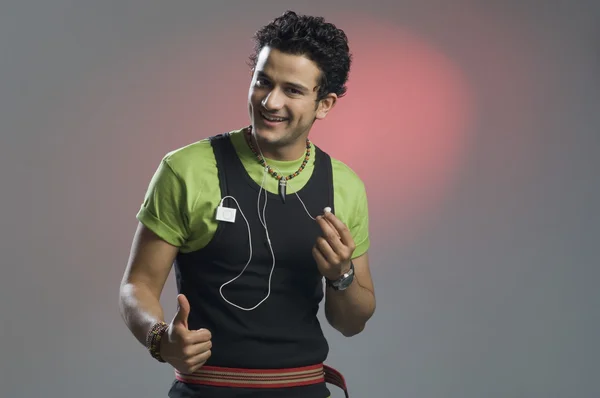 Man listening to music and showing thumbs up sign — Stock Photo, Image