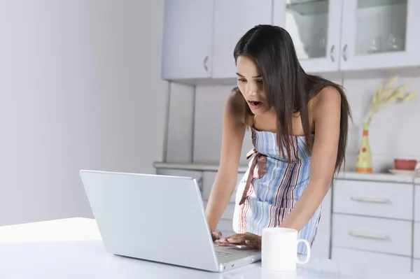 Vrouw met behulp van een laptop in de keuken — Stockfoto