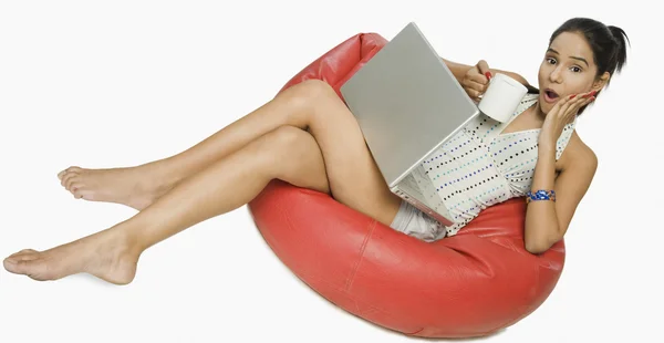 Bir fincan kahve ile bir dizüstü bilgisayar kullanan kadın — Stok fotoğraf