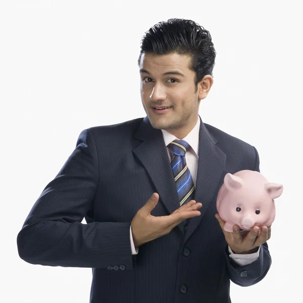 Бизнесмен, держащий свинью-банк — стоковое фото