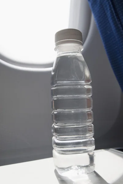 Botella de agua en bandeja de asiento en un avión — Foto de Stock