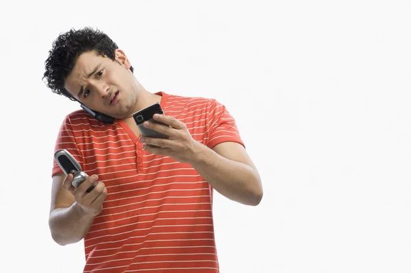 Человек, использующий несколько мобильных телефонов — стоковое фото