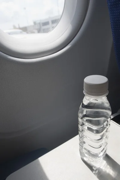 Botella de agua en bandeja de asiento en un avión — Foto de Stock