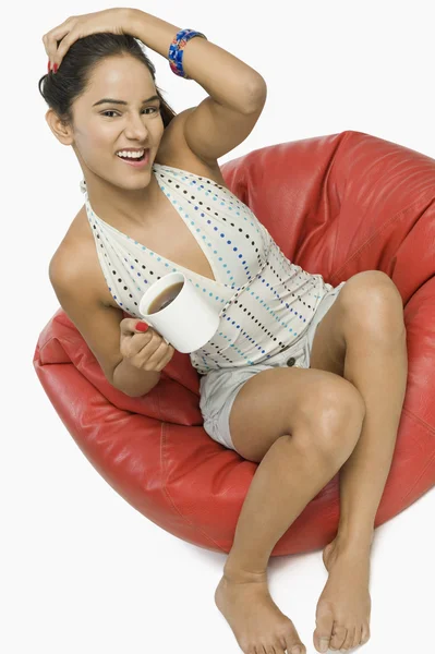 Mujer sentada en una bolsa de frijoles con una taza de café —  Fotos de Stock