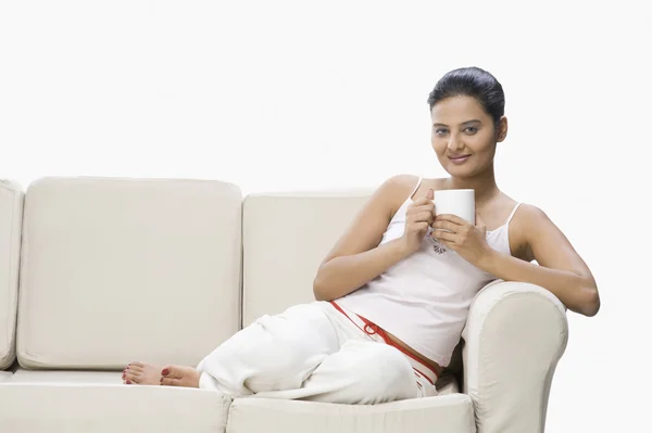 Frau genießt eine Tasse Kaffee auf einer Couch — Stockfoto