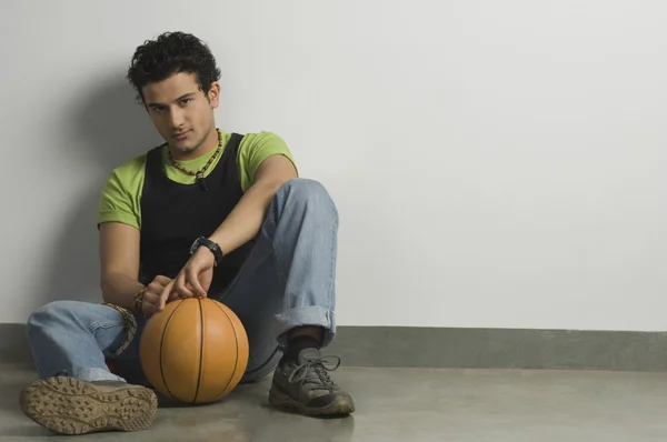 Homem sentado com uma bola — Fotografia de Stock