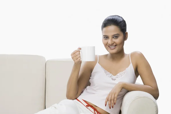 Frau genießt eine Tasse Kaffee auf einer Couch — Stockfoto