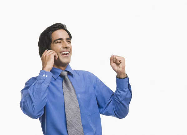 Businessman raising fist while talking on a mobile phone — Stock Photo, Image