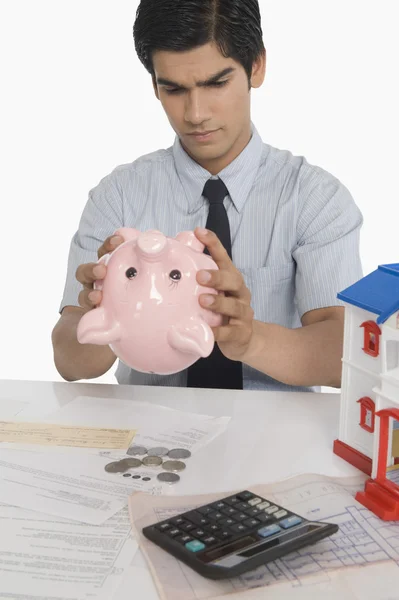 Real estate agent looking into a piggy bank — Stock Photo, Image