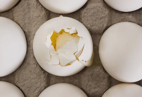 Huevo roto en una caja con otros huevos — Foto de Stock