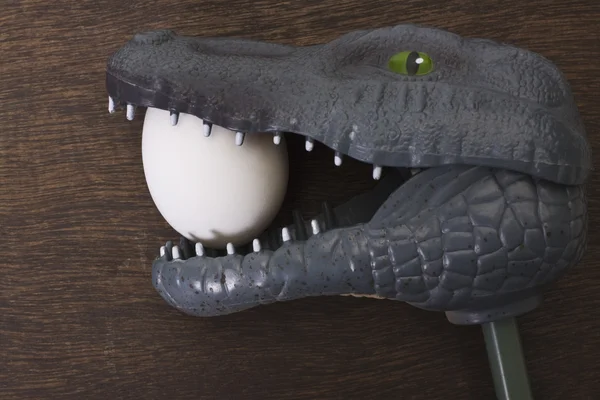 Toy crocodile holding an egg in jaw — Stock Photo, Image