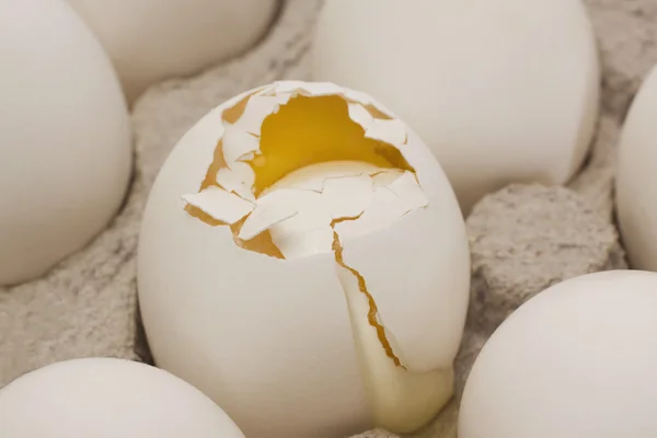 Huevo roto en una caja con otros huevos — Foto de Stock