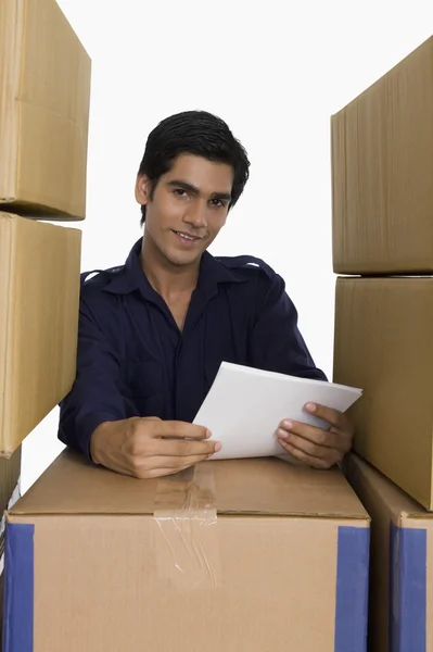 Store manager holding papers with cardboard boxes — Stock Photo, Image