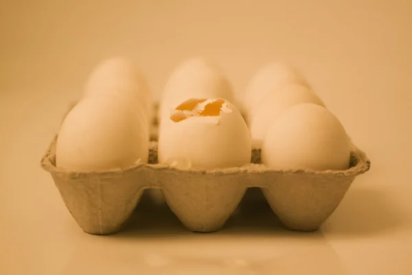 Uovo rotto in una scatola con altre uova — Foto Stock