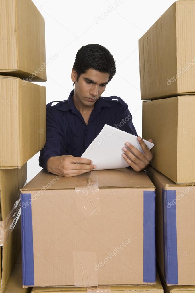 Store manager reading papers with cardboard boxes
