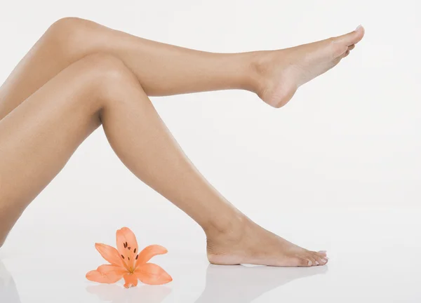 Woman's legs with a lily flower — Stock Photo, Image