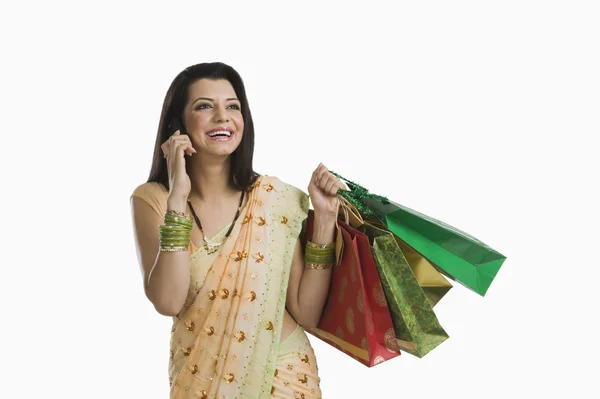 Mujer hablando en un teléfono móvil y sosteniendo bolsas de compras —  Fotos de Stock