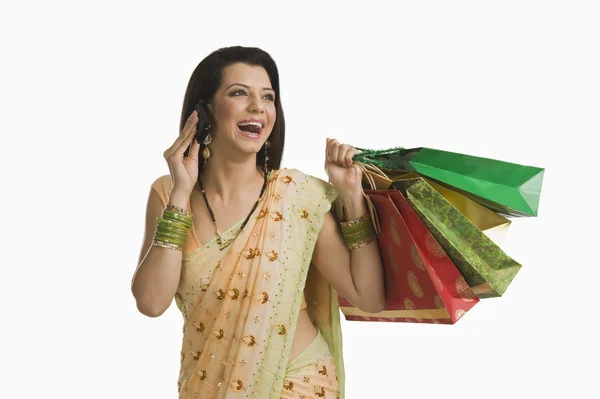 Mujer hablando en un teléfono móvil y sosteniendo bolsas de compras —  Fotos de Stock