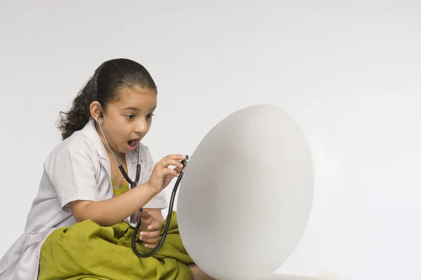 Mädchen untersucht Ei mit Stethoskop — Stockfoto