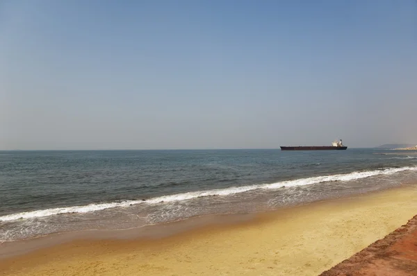 Playa con un barco de contenedores en el fondo — Foto de Stock