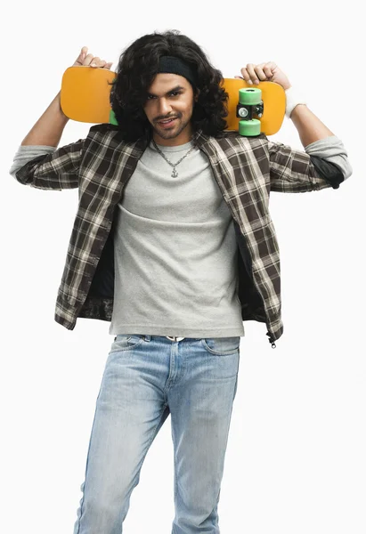 Man holding a skateboard on his shoulders — Stock Photo, Image
