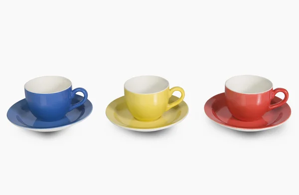 Colorful tea cups with saucers in a row — Stock Photo, Image