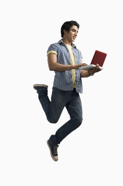 atlama ve bir dizüstü bilgisayarda çalışan adam
