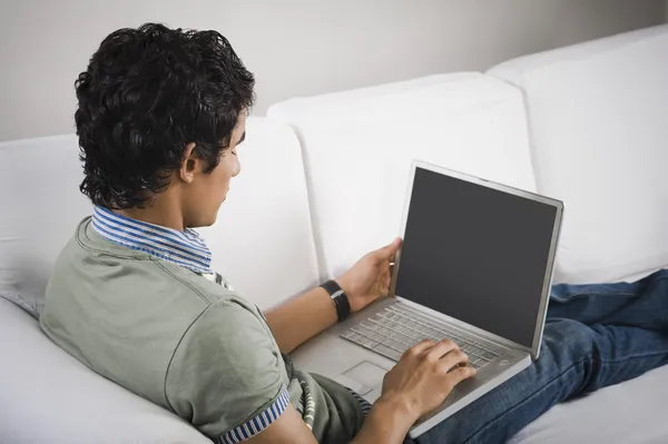 男子坐在沙发上，在笔记本电脑上工作 — 图库照片