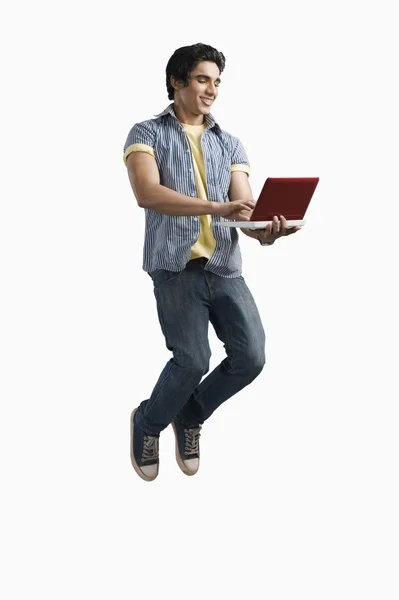 Studente universitario utilizzando un computer portatile e saltando — Foto Stock