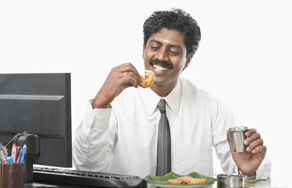 Businessman working in an office and having food — Stock Photo, Image