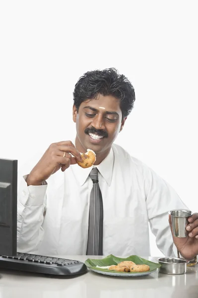 Businessman working in an office and having food — Stock Photo, Image