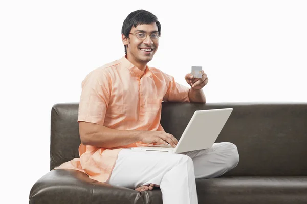 Bengali man holding a credit card and using a laptop — Stock Photo, Image