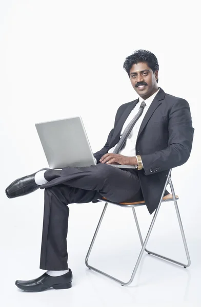 Businessman sitting on a chair and using a laptop — Stock Photo, Image