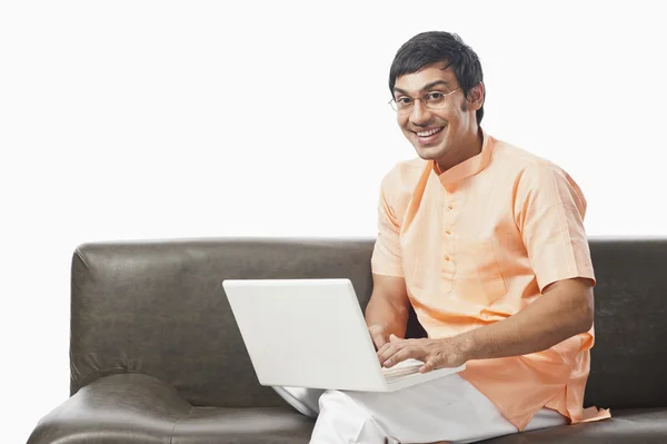 Bengali homem usando um laptop no sofá — Fotografia de Stock