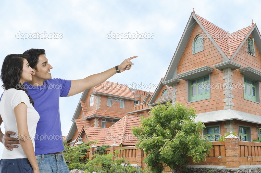 Man and wife and pointing towards a house