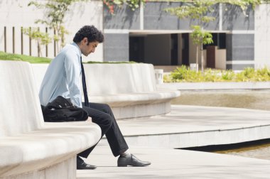 bir bahçede oturan işadamı